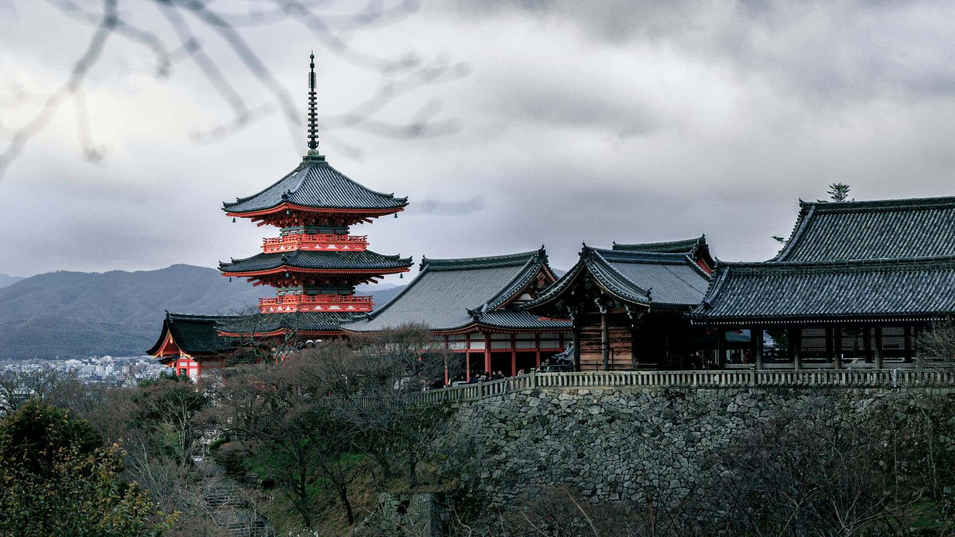 Kiyomizu-dera pagoda and temple buildings overlooking Kyoto under a dramatic cloudy sky